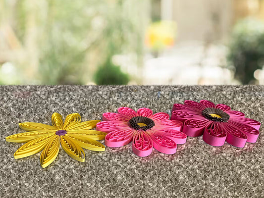 3 quilled flowers made using different strip widths laid side by side to show strip width difference.
