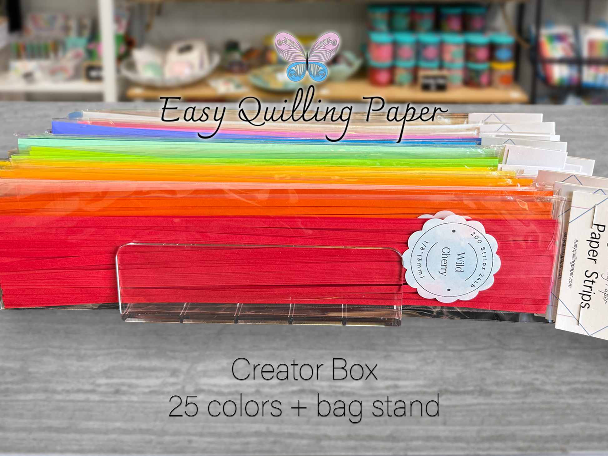 a clear plastic container. The container is labeled 'Wild Cherry' and '200 Strips 1/8 inch or 3mm'. The text 'Easy Quilling Paper' is displayed above the container. The text 'Creator Box 25 colors + bag stand' is displayed below the container.