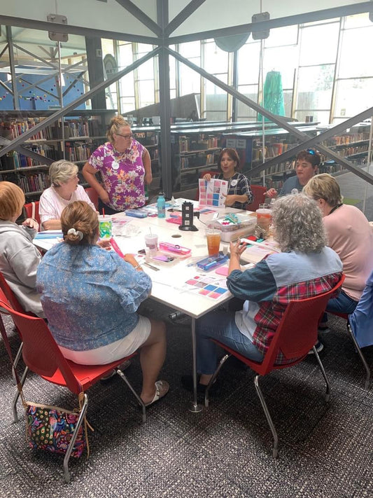 Quilling teacher instructing quilling students around a table.