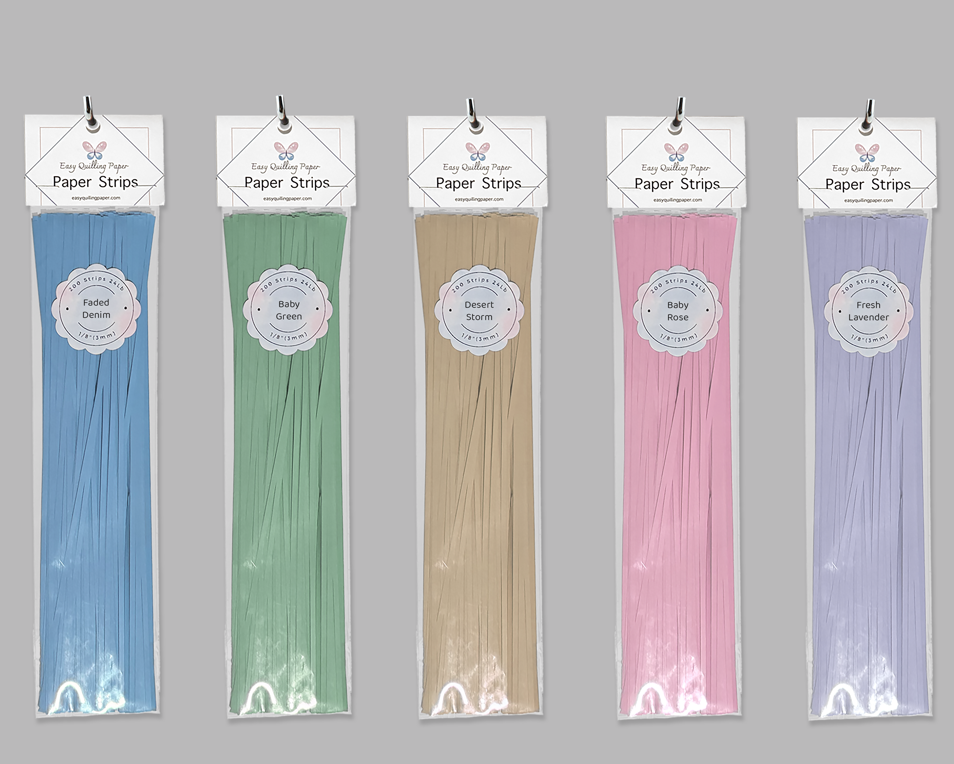 Flat quilling paper strips in blue, green, tan, pink, and purple packaged in resealable bags with hanging hole. bags of paper are hung on the wall side by side.